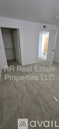 A room with a doorway leading to another room and a carpeted floor.