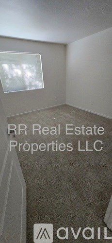 A room with a window and a carpeted floor.