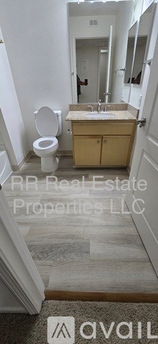 A bathroom with a toilet, sink, and mirror.