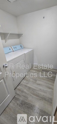 A small, empty room with a washing machine and a shelf.