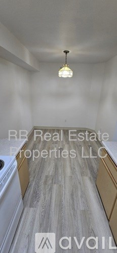 A well-lit kitchen with a white ceiling and a hanging light fixture.