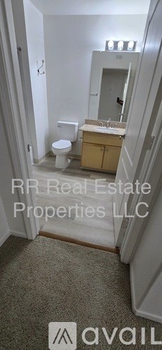 A bathroom with a toilet, sink, and mirror.