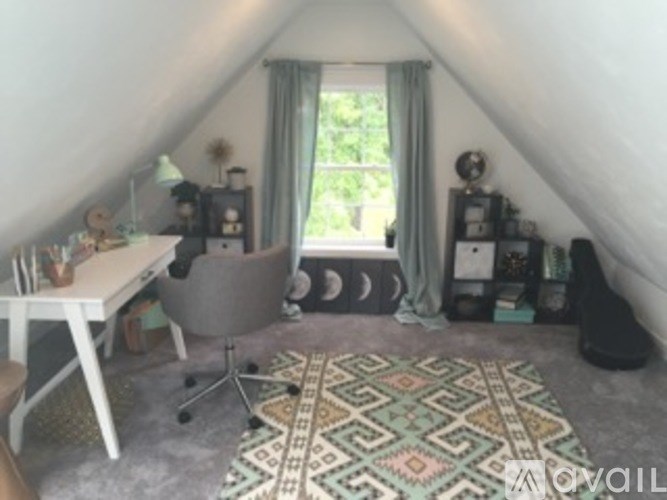 A room with a desk, chair, and a rug with a geometric pattern.