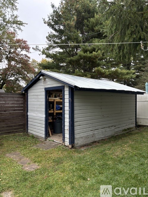 A shed with a metal roof and a door open to the side.