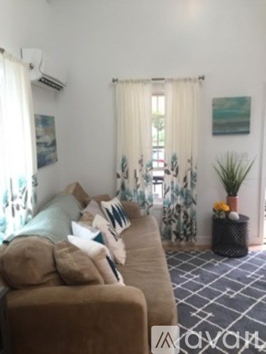 A living room with a tan couch and a plant on a black table.