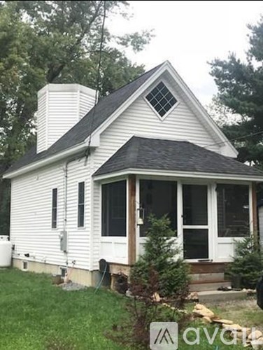 A white house with a black roof and a chimney.