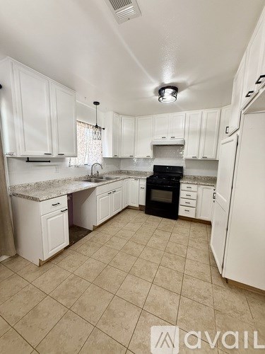 A kitchen with white cabinets and a tiled floor.