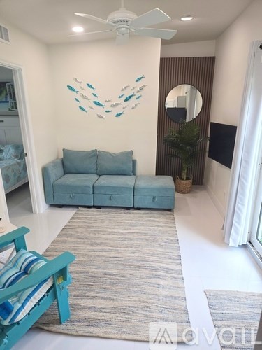 A living room with a blue couch and a fan on the ceiling.