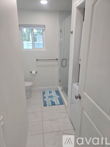 A bathroom with a toilet, sink, and a window.