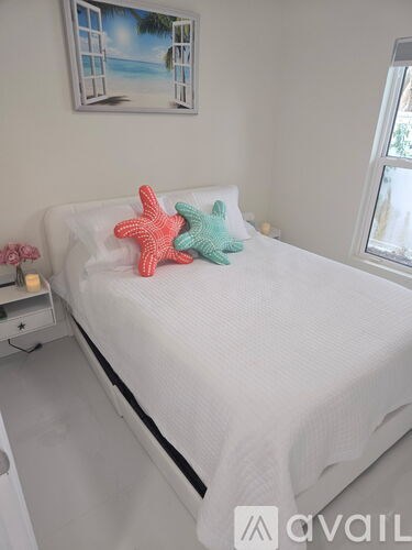 A white bed with a red starfish and a green starfish on it.