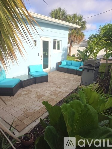 A blue house with a patio and a palm tree.