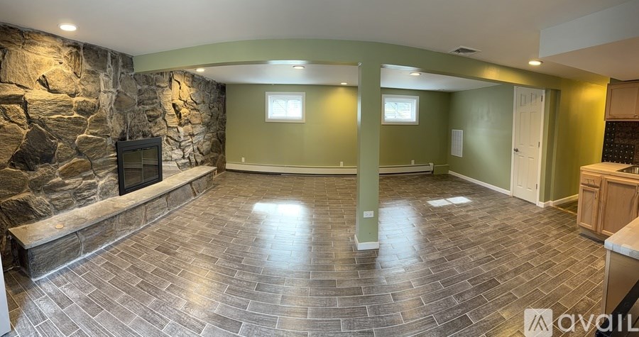 A stone fireplace in a room with a green wall.