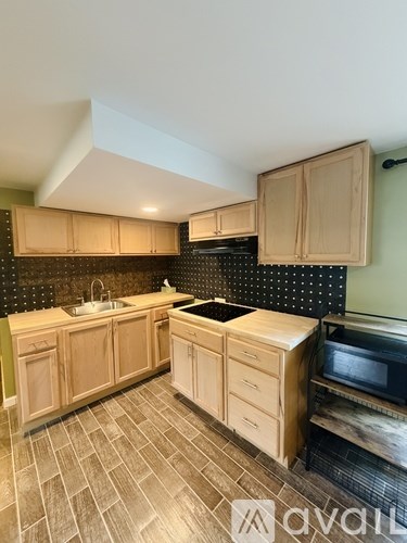A kitchen with wooden cabinets and a black tile backsplash.