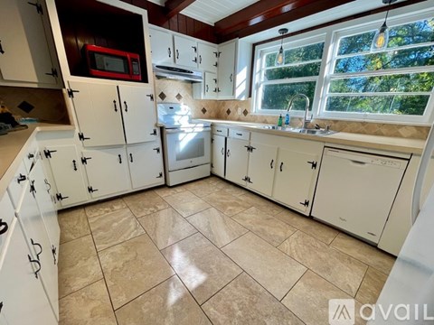 A kitchen with white cabinets and a tiled floor.