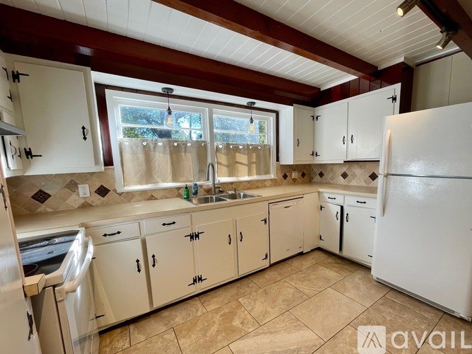 A kitchen with white cabinets and a tiled backsplash.