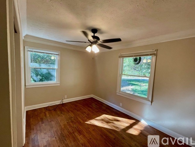 A room with a ceiling fan and two windows.