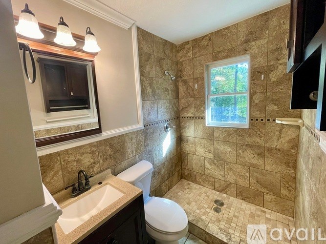 A bathroom with a beige tiled shower and a white toilet.