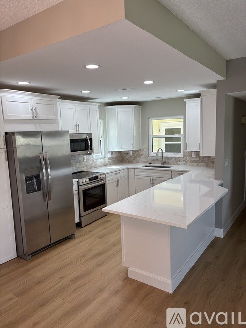 A kitchen with a refrigerator, microwave, oven, and sink.
