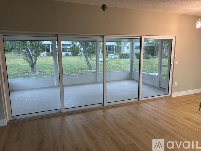 A room with a view of a yard through sliding glass doors.