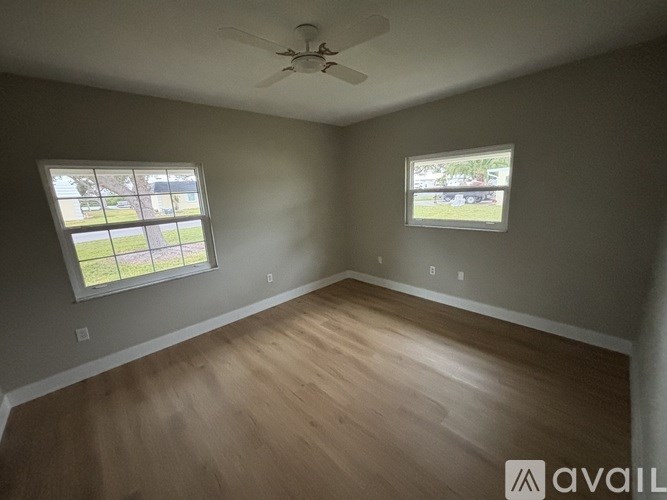 A room with a ceiling fan and two windows.