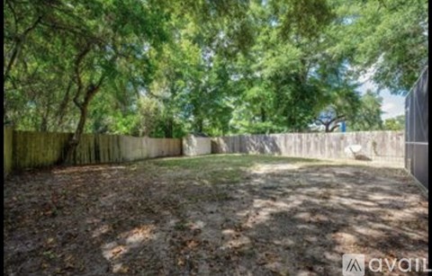 A backyard with a fence and trees.