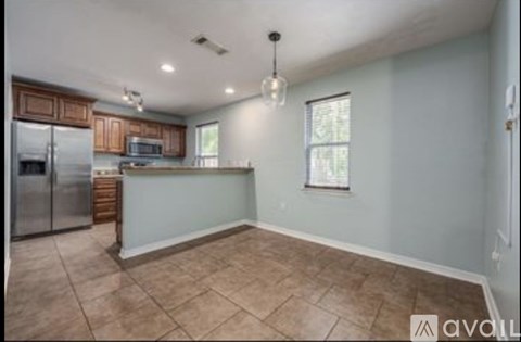 A kitchen with a refrigerator, microwave, and wooden cabinets.