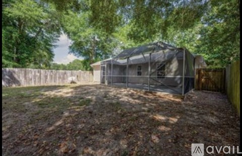 A backyard with a fence and a covered patio area.