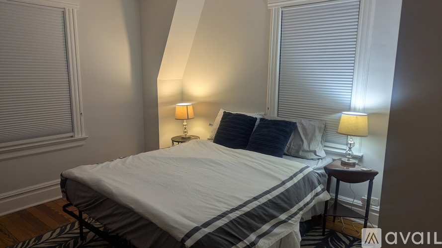 A bedroom with a bed, two lamps, and a striped comforter.
