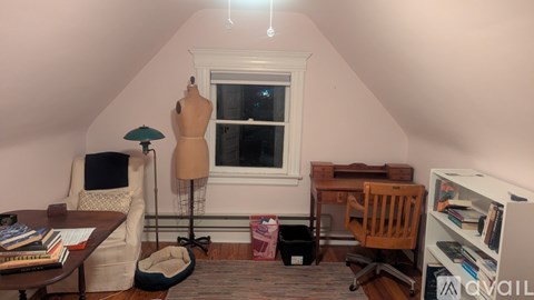 A room with a desk, chair, and a mannequin.