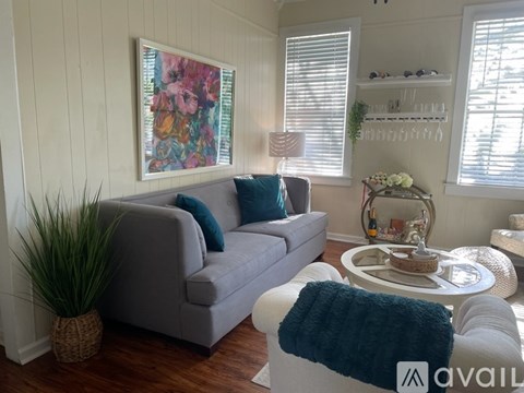 A living room with a grey couch, a white coffee table, and a large painting on the wall.