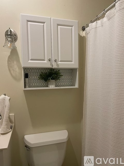 A white toilet sits under a cabinet in a bathroom.