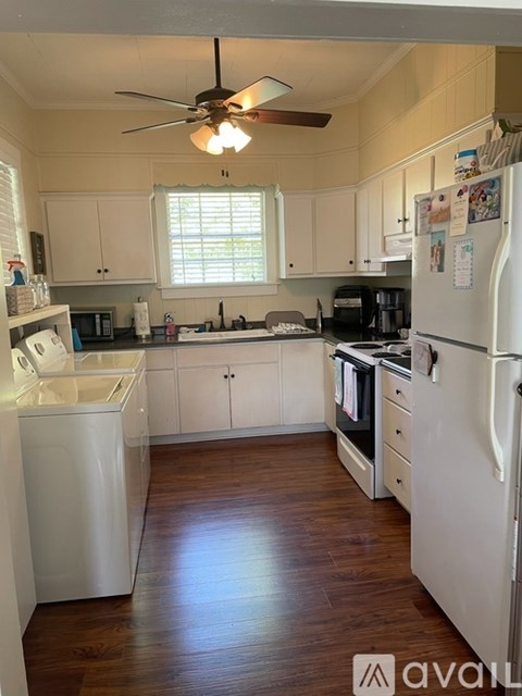 A kitchen with white appliances and wooden floors.
