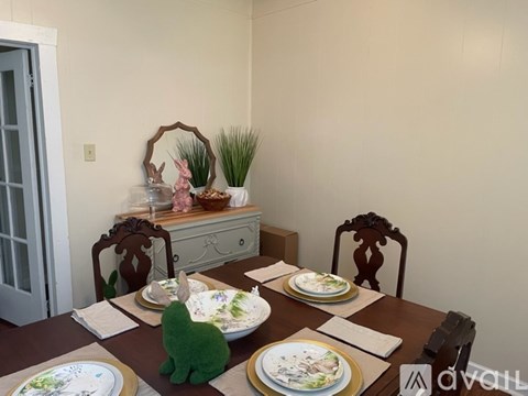 A dining table set with plates and a green cat toy.