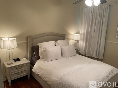 A bedroom with a large bed, two lamps, and a nightstand.