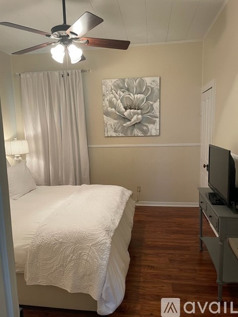 A bedroom with a bed, a television, and a painting on the wall.