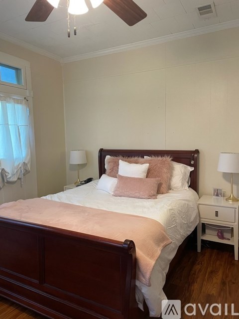 A bedroom with a bed, nightstand, and window.