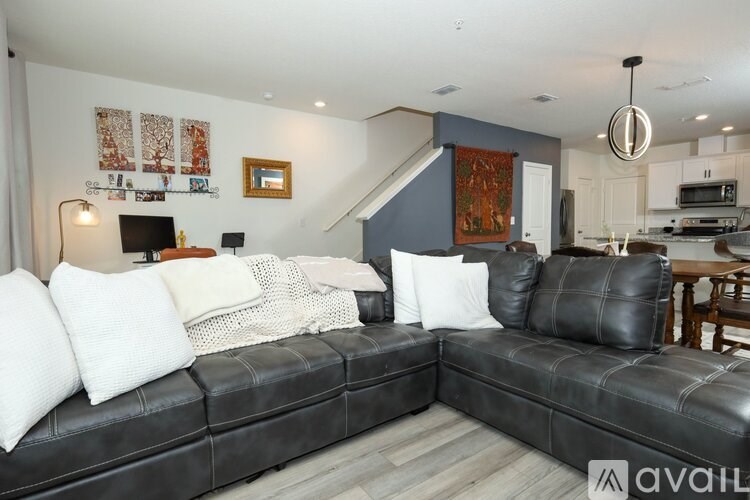 A black leather couch with white pillows in a living room.