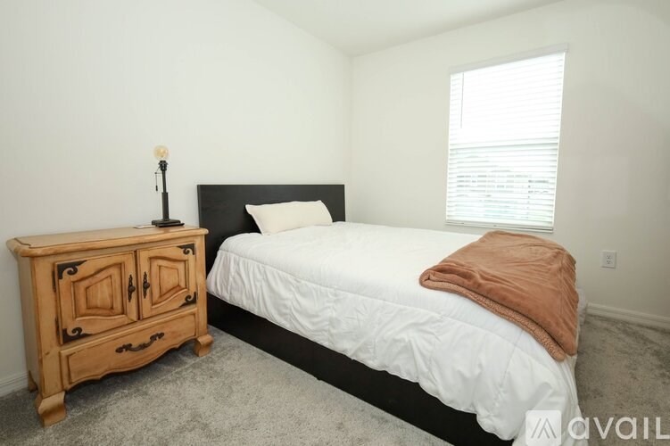 A bedroom with a bed, nightstand, and window.