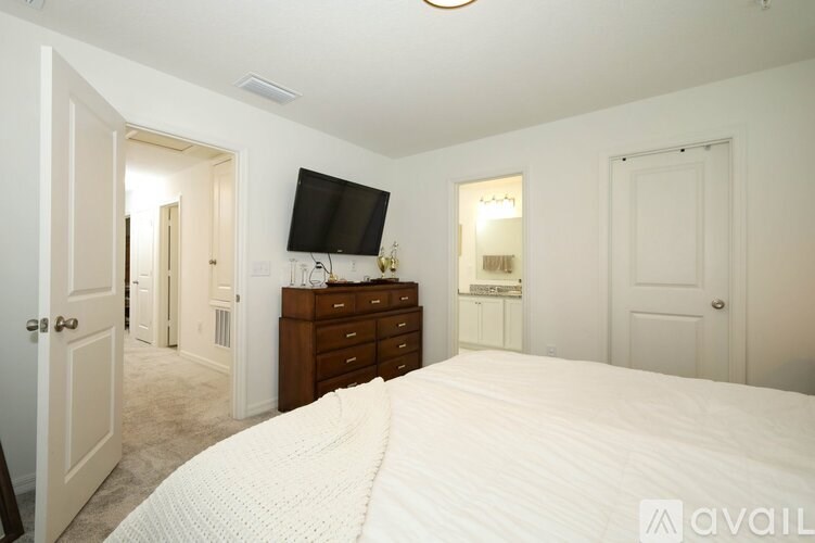 A bedroom with a large bed, a dresser, and a television.