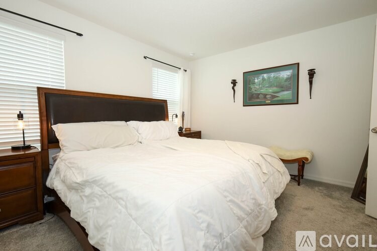A bedroom with a large bed and a painting on the wall.