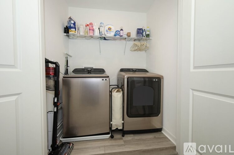 A kitchen with a stainless steel refrigerator and oven, and a shelf with various items on it.