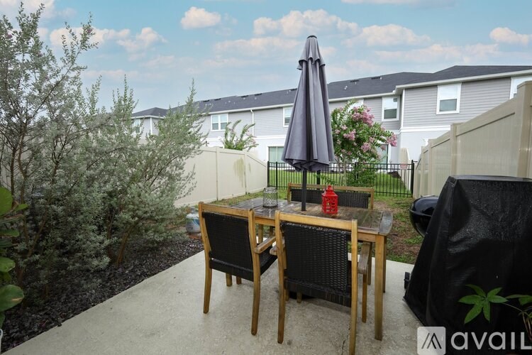 A patio with a table and chairs and a black umbrella.