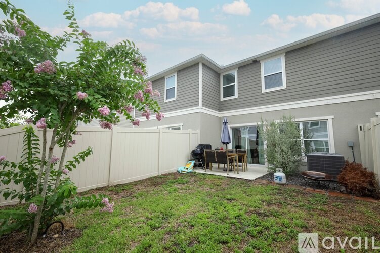 A house with a garden and a patio with a table and chairs.