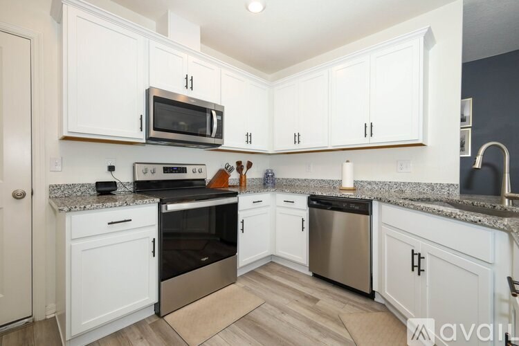A kitchen with white cabinets and a granite countertop.