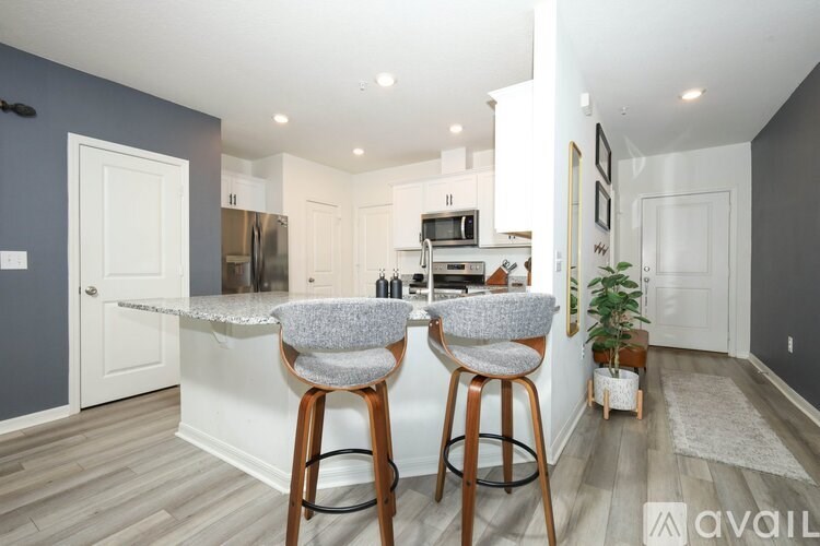 A kitchen with a bar area featuring two grey barstools.