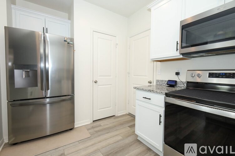 A kitchen with a stainless steel refrigerator and a black microwave above the stove.