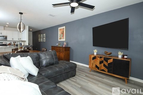 A living room with a black leather couch and a wooden cabinet.