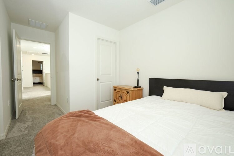 A bedroom with a bed, nightstand, and a window.