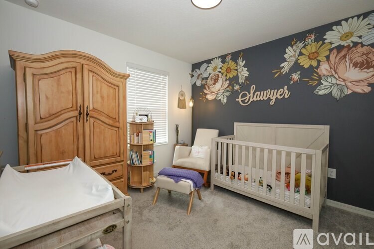 A nursery room with a mural of flowers and the word "Sawyer" on the wall.