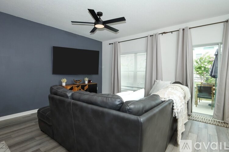 A black leather sofa in a living room with a flat screen TV mounted on the wall.